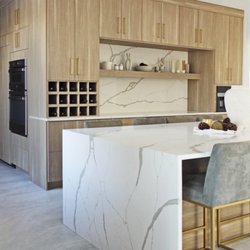 Monk's Home Improvements - Waterfall island countertop in quartz. Built-in wine rack. Light wood kitchen cabinetry.