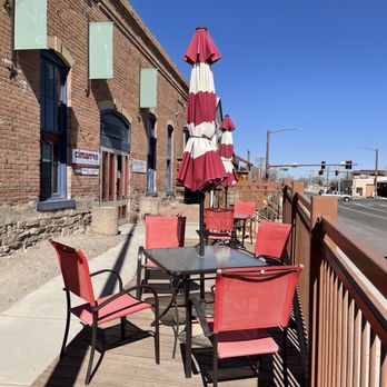 Cimarron Coffee Roasters - a patio with red chairs and umbrellas - Coffee Roasteries Near Me - Montrose, Colorado