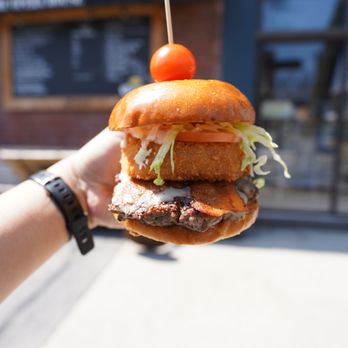 Riverside Burgers - a hand holding a hamburger - Burgers Near Me - Toronto, Ontario Riverside Burgers - a hand holding a hamburger - Burgers Near Me - Toronto, Ontario