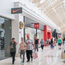 Fashion Outlets of Niagara Falls USA - Shoppers walk through a bright corridor past Nike, Under Armour and Express.