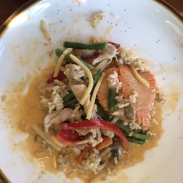 Red curry with pork and veggies with brown rice. - A white plate with a gold rim contains rice, vegetables, and a piece of salmon, with some food remnants and sauce.