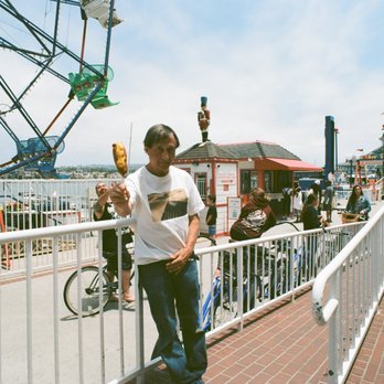 Balboa Fun Zone - Me with corn dog purchased from little restaurant just across from Ferris wheel. Man behind me is taking a selfie. He has big tattoo on arm. - Amusement Parks Near Me - Newport Beach, California Balboa Fun Zone - Me with corn dog purchased from little restaurant just across from Ferris wheel. Man behind me is taking a selfie. He has big tattoo on arm. - Amusement Parks Near Me - Newport Beach, California