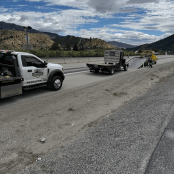 Timberline Towing and Recovery - A white tow truck and a flatbed truck are on the side of a highway, with mountains in the background under a cloudy sky. - Towing Near Me - Wenatchee, Washington Timberline Towing and Recovery - A white tow truck and a flatbed truck are on the side of a highway, with mountains in the background under a cloudy sky. - Towing Near Me - Wenatchee, Washington