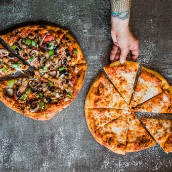 Doryland Pizza - two people holding slices of pizza - Pizza Near Me - Pacific City, Oregon Doryland Pizza - two people holding slices of pizza - Pizza Near Me - Pacific City, Oregon