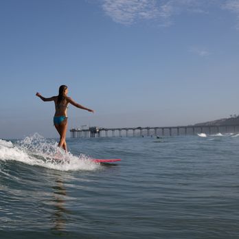 Surf Diva Surf School - Learn to longboard at La Jolla Shores, perfect to surf or bodyboard. Scripps beach in the background. Surfboard + wetsuit rentals available - Surf Shop Near Me - La Jolla, California