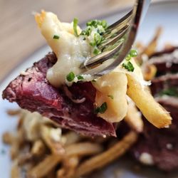Stock Cafe - A fork holding a piece of the Hanger Steak with some fries full of the Fondue.