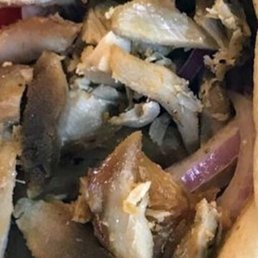 Chicken Gyro - A detailed close-up of chicken meat pieces, showing a mix of cooked and overcooked, rubbery-looking portions, with some bones and skin visible.