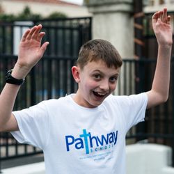 Pathway School - A boy smiling and lifting his hands up