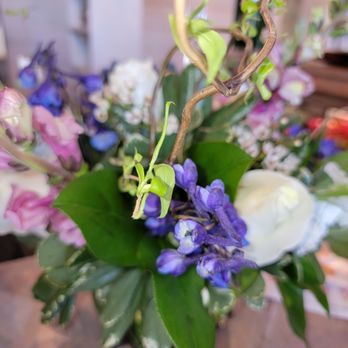Devonwoods - A bouquet of mixed flowers with purple, white, and pink blossoms, green foliage, and twisting branches, arranged in a container. - Florists Near Me - Reno, Nevada