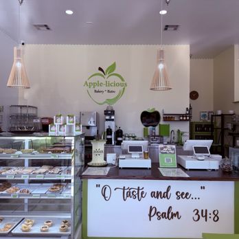 Apple-licious - Bakery interior featuring display cases with baked goods, a bakery counter with cash registers, and a logo on the wall reading 'Apple-licious Bakery Bistro.' - Bakeries Near Me - Spring, Texas