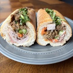 Left: 02. Banh Mi Dac Biet Right: 01. Banh Mi Ngon Combination. Other halves are on another plate.