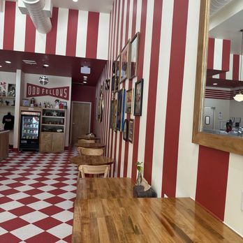 Oddfellows - The image shows the inside of Oddfellows, featuring red and white striped walls, wooden tables, and framed pictures. A mirror and a small plant are also visible. - Ice Cream & Frozen Yogurt Near Me - Spring, Texas