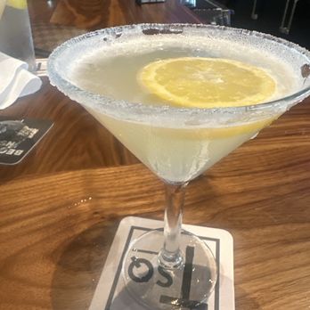 Tavern in the Square - A lemon cocktail in a martini glass with a salted rim and lemon slice garnish, placed on a bar counter. - Sports Bars Near Me - Salem, New Hampshire