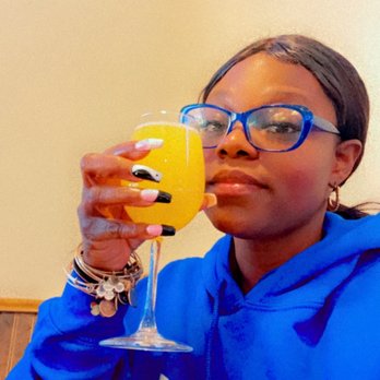 Shawano’s Cafe - Me - A woman with glasses and a blue hoodie is holding a glass of orange juice inside Shawano's Cafe in Shawano, Wisconsin. - Seafood Near Me - Shawano, Wisconsin