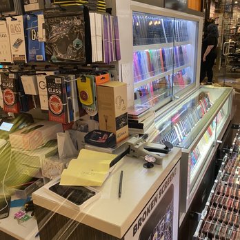 Chicago Ridge Mall - Fix & More - Checkout counter at a retail store with stationery, phone accessories, and a glass fridge with colorful products, located near a glass storefront. - Shopping Centers Near Me - Chicago Ridge, Illinois