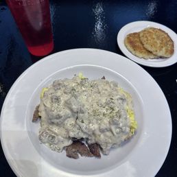 Biscuits and gravy with sausage and scrambled eggs and a side of potato cakes