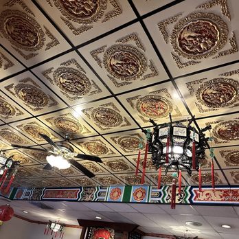 Mandarin Restaurant - the ceiling of the restaurant - The ceiling displays a grid of decorative panels with gold and red intricate patterns, likely inspired by Asian art. There are ceiling fans and traditional lantern-style chandeliers hanging from the ceiling, with red tassels and candles. The decor suggests an Asian restaurant setting with cultural design elements. - Chinese Near Me - Albuquerque, New Mexico