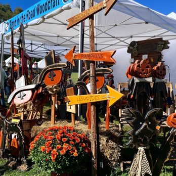 The Pro Found Market - Colorful wooden signs indicate directions to pumpkins, hayrides, and a corn maze at an outdoor market with fall decorations and crafts. - Flea Markets Near Me - Lancaster, Massachusetts