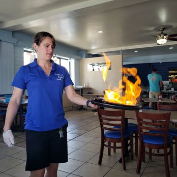 Neptune Grill - a woman holding a frying pan on fire - American Near Me - Gulfport, Florida Neptune Grill - a woman holding a frying pan on fire - American Near Me - Gulfport, Florida