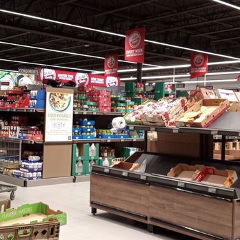 ALDI - The image shows an interior view of a grocery store, featuring produce displays with cardboard boxes and bins, shopping carts, and signage. The store has bright lighting and organized sections, with visible ALDI branding and product arrangements, typical of a supermarket setting. - Grocery Near Me - South Windsor, Connecticut