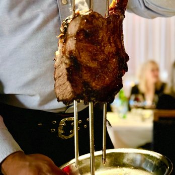Fogo de Chão - a man holding a plate of food - Steakhouses Near Me - Lone Tree, Colorado