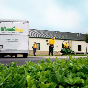 The Grounds Guys - a man mowing bushes - Landscaping Near Me The Grounds Guys - a man mowing bushes - Landscaping Near Me