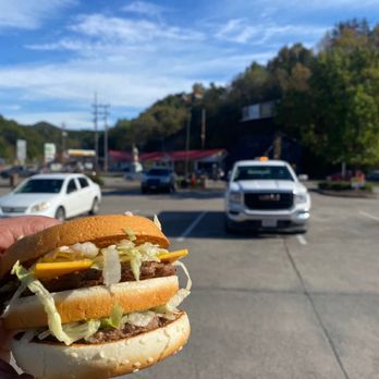 McDonald's - a hand holding a hamburger in a parking lot - Fast Food Near Me - Elkins, West Virginia