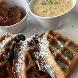 Waffles plate with two sides, grits and pork bacon.