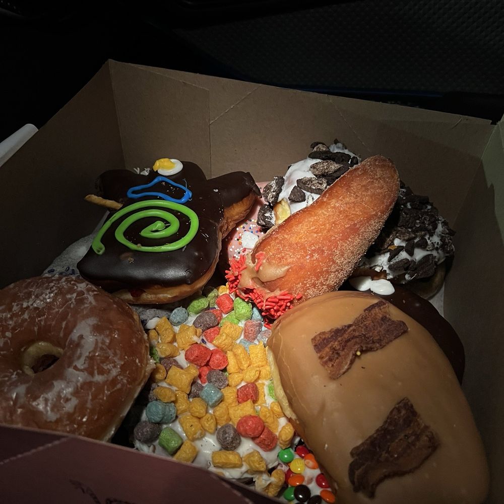 Voodoo Doughnut - The Voodoo Dozen selection we received. Notice the burned bacon on the maple bar. Not good! - Donuts Near Me - Seattle, Washington Voodoo Doughnut - The Voodoo Dozen selection we received. Notice the burned bacon on the maple bar. Not good! - Donuts Near Me - Seattle, Washington