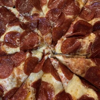 Roaring Rapids Pizza Co - Pepperoni pizza - A close-up image of a pepperoni pizza featuring a layer of melted cheese topped with numerous slices of pepperoni. The pizza is cut into slices, revealing the cheese stretch and crispy edges of the pepperoni. The crust appears golden brown and slightly thick, with some areas showing a slight crispiness. The toppings are evenly distributed across the pizza, highlighting the classic pepperoni pizza style. - Pizza Near Me - Eugene, Oregon
