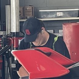 Worker struggling to get tire mounted while wearing headphones Worker struggling to get tire mounted while wearing headphones