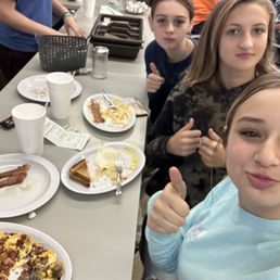 a group of people sitting at a table with plates of food a group of people sitting at a table with plates of food
