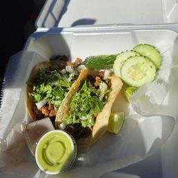 Two steak tacos with two sauces and a roasted jalapeño