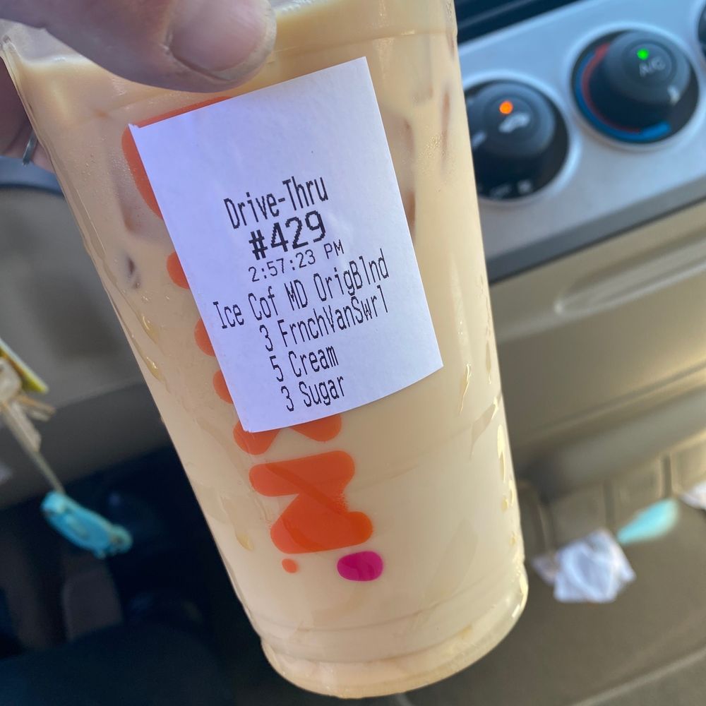  a hand holding a cup of iced coffee
