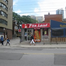 people walking in front of a pizza shop