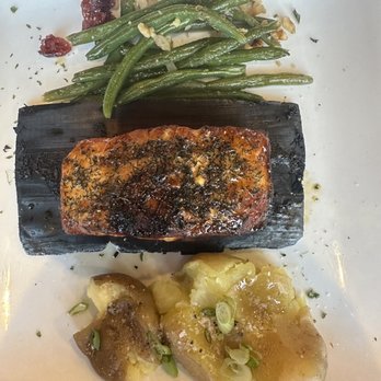 NaCl + H2O - Cedar plank salmon - The image shows a serving of cedar plank salmon with a dark glaze, green beans with garlic, and mashed potatoes topped with chopped green onions. - Cocktail Bars Near Me - Rolla, Missouri