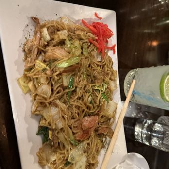 Chaplin's - Chicken Yakisoba - A rectangular white plate holds chicken yakisoba noodles with vegetables, garnished with pickled ginger, on a dark wooden table. - Cocktail Bars Near Me - Washington, DC, District of Columbia