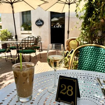 Coronet Cafe - Patio - A cafe patio features two drinks on a white metal table, with table number 28, surrounded by umbrellas and outdoor seating. - Cafes Near Me - Tucson, Arizona