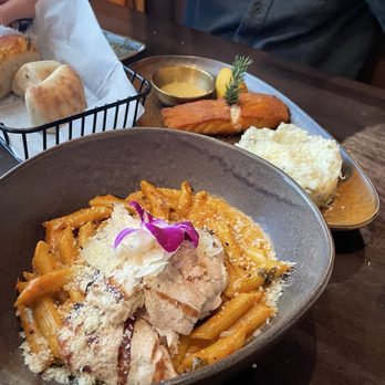 Salute Italian Restaurant - Penne a la Vodka with Chicken, Salmon Dijon with mashed potatoes in the background. - Italian Near Me - Frisco, Texas