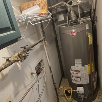Unbeeliveble Work - New hot water heater - A Rheem water heater is installed in a utility space, with visible plumbing, electrical wiring, and a small access panel on the wall. - Plumbing Near Me - Thornton, Colorado