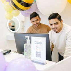 Two happy employees ready to help you out! The cheerful bee balloon in the background is a fun touch.