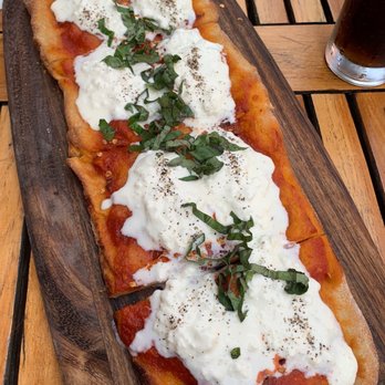 Tarallucci e Vino Upper West Side - a pizza on a wooden cutting board - Italian Near Me - New York, New York Tarallucci e Vino Upper West Side - a pizza on a wooden cutting board - Italian Near Me - New York, New York
