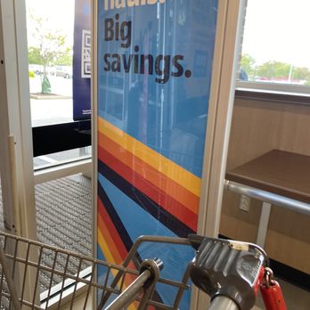 ALDI - Inside an ALDI store, a shopping cart is in front of a colorful promotional sign with the text 'Big. hauls. Big. savings.' near a window showing the parking lot. - Grocery Near Me - Laurel, Maryland