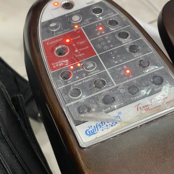 Try Me Nails - A close-up of a massage chair control panel featuring numerous buttons, indicator lights, and labels for functions such as knead, flap, knock, air mode, and intensity. The panel has a wood-like finish and includes labels for settings like range, width, and manual options. The control panel is part of a massage chair, with a partial view of the surrounding area and a Gulf sticker at the bottom. - Nail Salons Near Me - Darien, Illinois