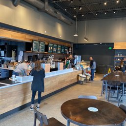 a woman standing at a counter in a coffee shop