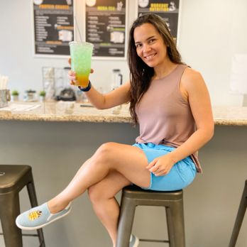 Smart Nutrition Tx - a woman sitting on a stool holding a drink - Juice Bars & Smoothies Near Me - Spring, Texas