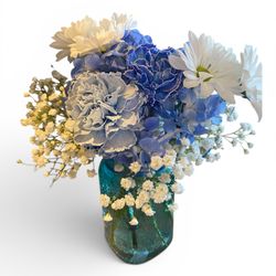Dooley's Florist & Gifts - True Blue
blue hydrangea, blue carnations, white daisies, gypsophylia in a blue hammered glass jar