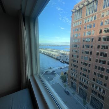 Seaport - Odd rooms have a nice view of the airport across the bay. - A cityscape view from a hotel window showing a street, waterfront, and a tall brick building on the right. - Hotels Near Me - Boston, Massachusetts