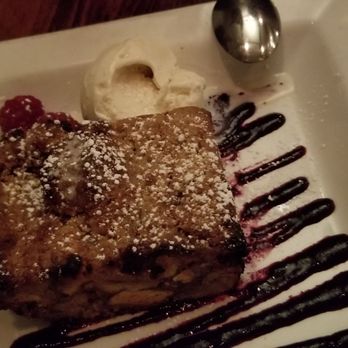 Label - Bread pudding. Apple fritter mixed with glazed donut, rolled in crème fraîche, served over a berry glaze with Pittsford dairy ice cream. - New American Near Me - Pittsford, New York