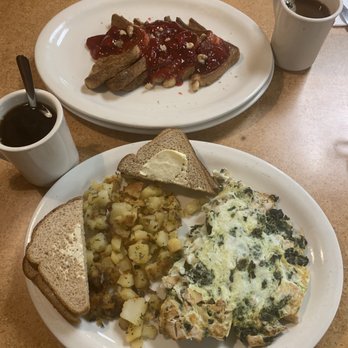 Fisher's Cafe - Stuffed French Toast (cream cheese, walnuts and strawberries ) The Chelsea Boy (grilled chicken, spinach and egg whites) - A breakfast meal with two plates: one with French toast topped with strawberries and syrup, and another with scrambled eggs, hash browns, and toast, accompanied by two cups of coffee. - Cafes Near Me - Hasbrouck Heights, New Jersey